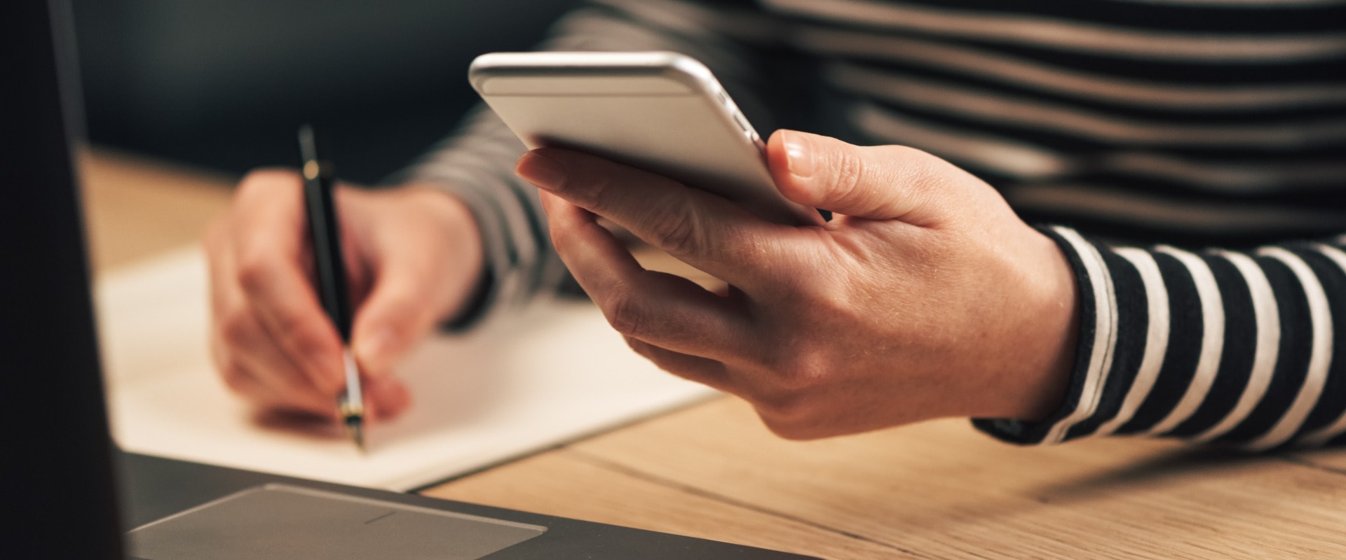 Frau schreibt Kontaktliste vom Telefon in die Geschäftsagenda